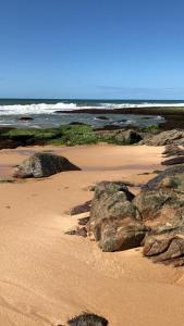 una playa con rocas en la arena y el océano en B&B JPA Casa ANSELMO en Salvador