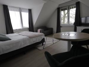 Hotel Zuideinde في Nieuwkoop: غرفة نوم بسرير وطاولة وكراسي