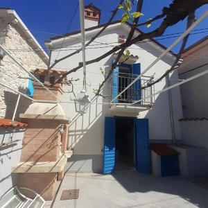 una casa blanca con una puerta azul y escaleras en House Rozalia en Susak
