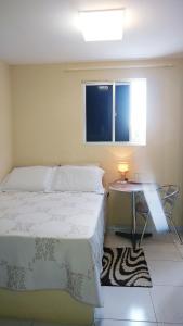 a bedroom with a bed and a table and a window at Suíte INDIVIDUAL com Ar condicionado em AP Compartilhado in João Pessoa