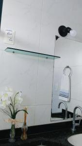 a bathroom sink with a mirror and a vase with flowers at Suíte INDIVIDUAL com Ar condicionado em AP Compartilhado in João Pessoa
