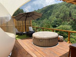 um pátio com um guarda-sol e uma banheira de hidromassagem num deque em La Estela Bubble Glamping em Mazamitla