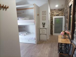 Zimmer mit 2 Etagenbetten und einem Tisch in der Unterkunft Albergue Aldea da Pedreira in Teo
