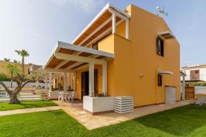 una casa amarilla con un patio verde en Lo Scorcio Sullo Stagnone, en Marsala