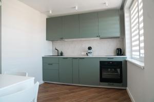 eine Küche mit grünen Schränken und einem schwarzen Backofen in der Unterkunft Grey Green Studio Apartment in Birštonas