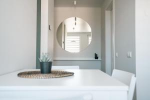 ein Esszimmer mit einem weißen Tisch und einem Spiegel in der Unterkunft Grey Green Studio Apartment in Birštonas