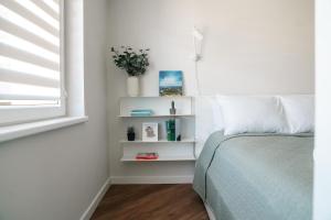 a bedroom with a bed with white shelves and a window at Grey Green Studio Apartment in Birštonas