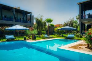 - une piscine avec des chaises et des parasols à côté d'un bâtiment dans l'établissement Villas 95 Appart'Hôtel, à Marrakech
