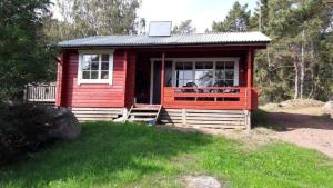 a red tiny house with people in the window at Mellangårds stugor - Stockstugan in Föglö