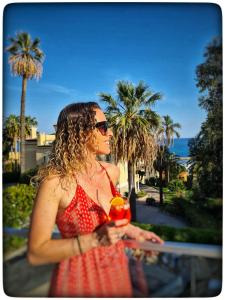 une femme en robe rouge tenant un verre dans l'établissement Le Vallaya Suites & Spa, à Menton