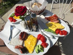 zwei Teller mit Frühstückslebensmittel auf einem Tisch mit Rosen in der Unterkunft InTown Guesthouse Shkoder in Shkodra