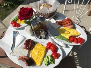 two plates of breakfast food on a table with roses at InTown Guesthouse Shkoder in Shkodër