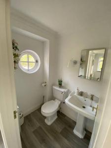 a white bathroom with a toilet and a sink at Country cottage with private garden close to beach in St. Mary