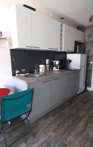 a kitchen with white cabinets and a green chair at Le PATSA de Vouillé in Vouillé