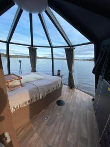 a bedroom on a boat with a large window at Yggdrasil Igloo Värmland in Töcksfors