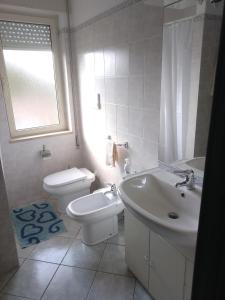 a white bathroom with a toilet and a sink at MaRo Apartment in Cala Liberotto