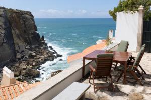 uma mesa e cadeiras numa varanda com vista para o oceano em Um Lugar ao Sol Beach House Azenhas do Mar em Sintra