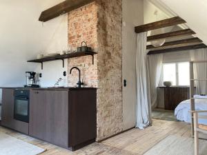 a kitchen with a counter and a brick wall at Österlen loft in Tomelilla