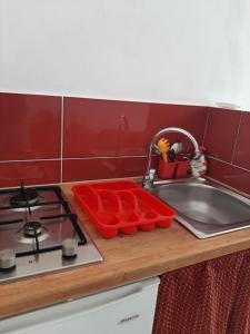 kuchnia ze zlewem, kuchenką i czerwoną ścianą w obiekcie La Melagrana w mieście Castellammare del Golfo