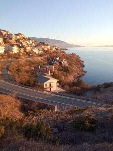 a road with houses on a hill next to the water at Marijana in Senj