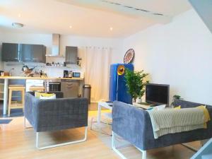 a living room with two blue chairs and a kitchen at A la Grosse Armée - Dans hôtel particulier, hypercentre avec garage, au calme in Bourges