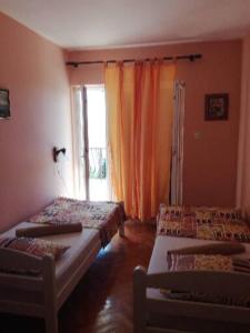 a room with two beds and a window with orange curtains at Marijana in Senj