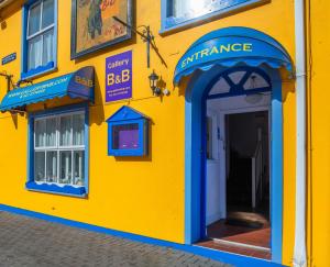 金塞爾的住宿－The Gallery B&B, the Glen, Kinsale ,County Cork，黄色建筑,入口处有蓝色门廊