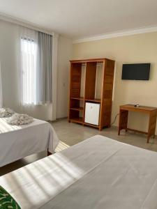 a hotel room with two beds and a television at Minas Hotel Unidade Centro in Mariana