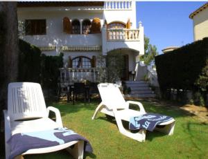 two chairs sitting in the grass in front of a house at Chalet a 100m de la playa de Cristal, Pino Alto in Hospitalet de l'Infant