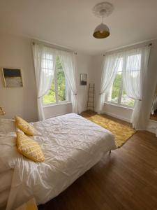 a bedroom with a bed and two large windows at Maison de Montgibaud in Montgibaud