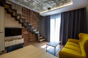a living room with a yellow couch and a brick wall at Apartamenty Posejdon in Łazy