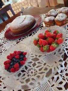 einen Tisch mit Teller mit Erdbeeren, Blaubeeren und Gebäck in der Unterkunft Agriturismo Fruttirossi in Trofarello