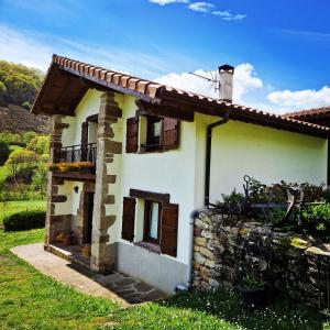 a small white house with a stone wall at Alberroakoborda in Ituren