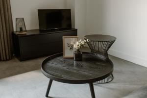 a table with a picture and a chair in a room at De la Rue Vakantiesuites in Sleeuwijk