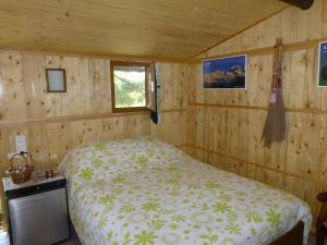 - une chambre avec un lit dans une pièce en bois dans l'établissement CABANE perchée dans les arbres et terrasse ensoleillée, à Robion