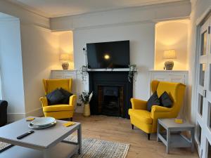 a living room with two yellow chairs and a fireplace at Heathcliff - 5 Bedroom House in Town Centre in Pembrokeshire