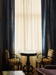a table and two chairs in front of a curtain at The Hotel Chelsea in New York