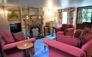 a living room with red chairs and a fireplace at Laburnum Cottage Broadway in Broadway