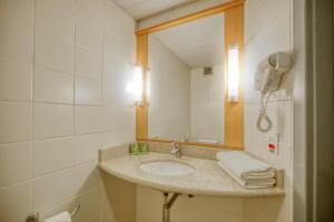 a bathroom with a sink and a mirror at HUS HOTEL Dourados in Dourados