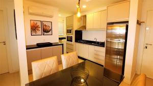una cocina con armarios blancos y una mesa con sillas. en 1044 - Apartamento de 01 dormitório em Bombinhas - Residencial Egídio Pinheiro 101 B, en Bombinhas