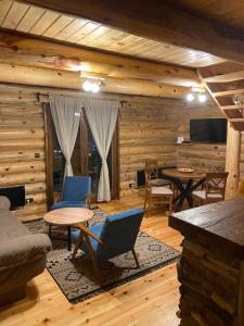 a living room with wooden walls and tables and chairs at Brvnare Park Borova in Zlatibor