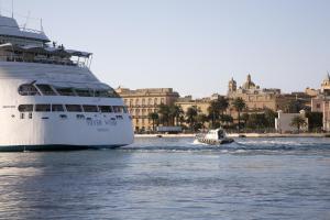 una nave da crociera e una piccola barca in acqua di B&B La Terrazza Sul Porto a Trapani