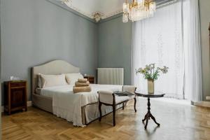 a bedroom with a bed and a table and a chandelier at Dimora delle Maestranze (Ortigia) in Siracusa