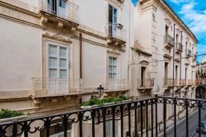 a building with balconies and a fence next to a street at Dimora delle Maestranze (Ortigia) in Siracusa