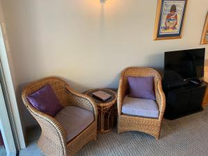 two wicker chairs and a table in a living room at King's View Lodge in Whangaroa