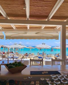 a beach with tables, chairs and umbrellas at Acrogiali Beach Hotel Mykonos in Platis Gialos