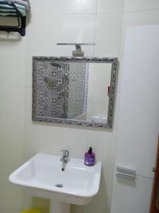 La salle de bains est pourvue d'un lavabo blanc et d'un miroir. dans l'établissement bel appart refait à neuf sur Tamouda Bay Tétouan, à Fnideq