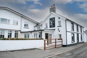 un edificio blanco con una señal negra. en The Lamb of Rhos en Llandysul