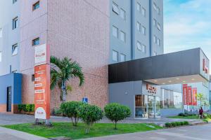 Un edificio alto con árboles delante. en HUS HOTEL Dourados, en Dourados