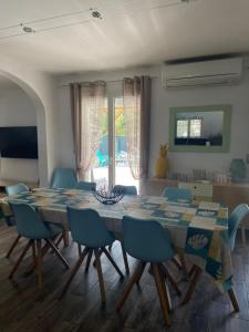 uma sala de jantar com uma mesa e cadeiras azuis em Maison 8-10 pers avec piscine aux portes de St Aygulf em Fréjus